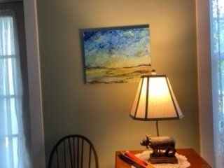 A table with a lamp and a painting on the wall above it