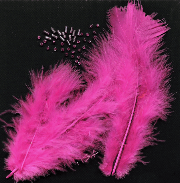 Pink feathers and beads on a black surface
