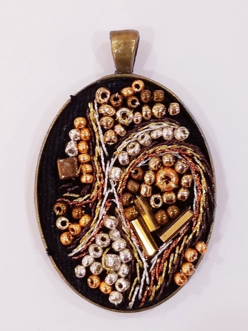 A black and gold pendant with beads on it