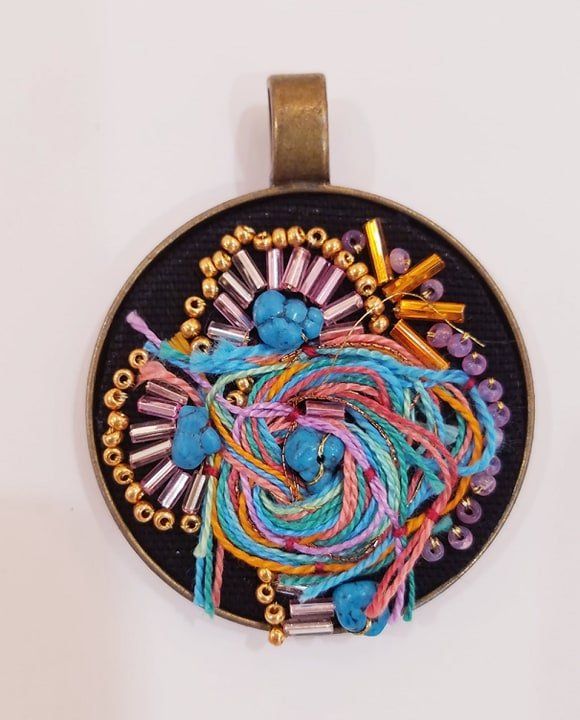 A pendant with yarn and beads on it