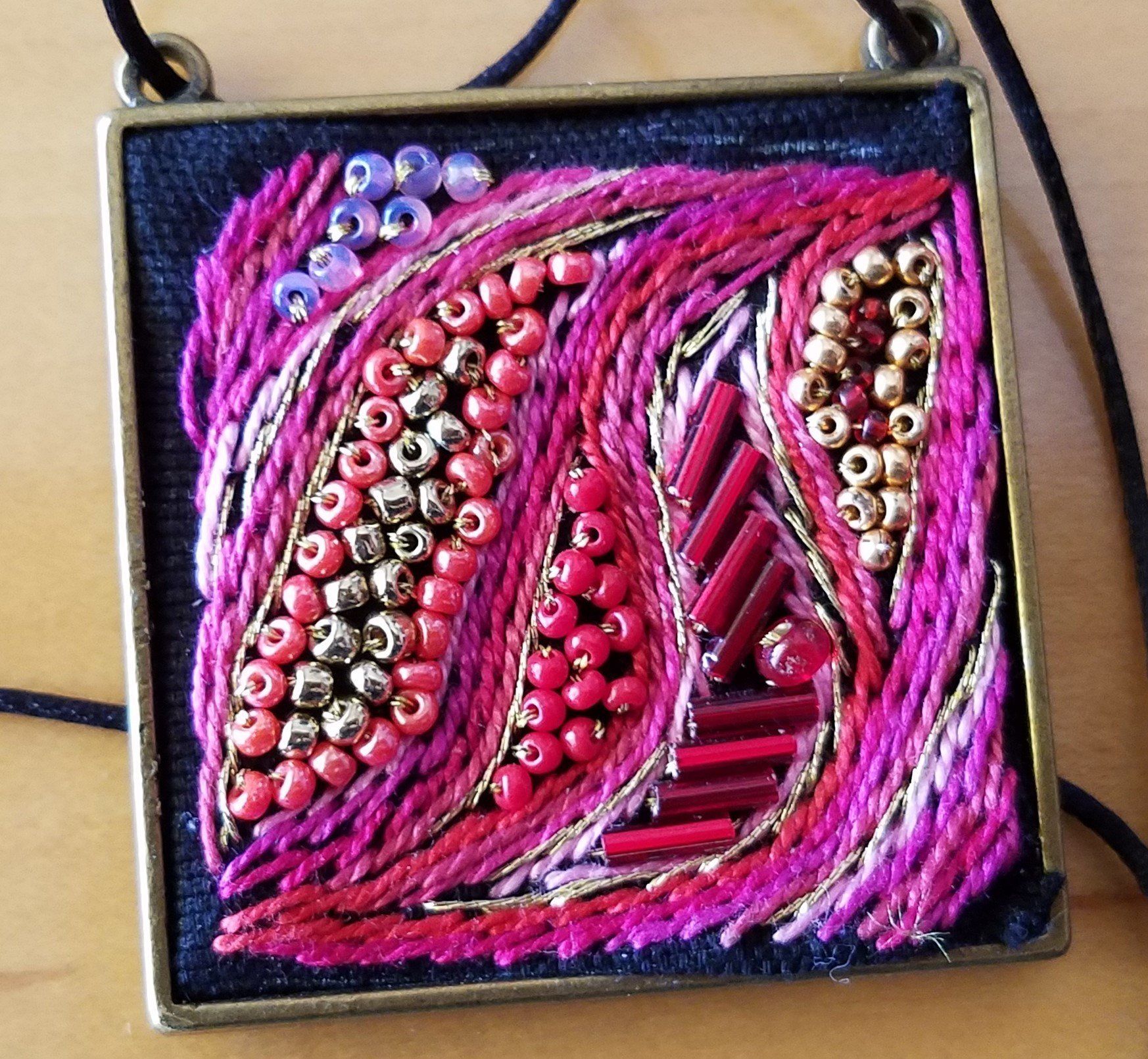 A square pendant with pink beads on it