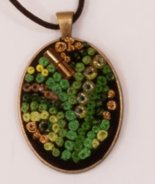 A pendant with green and yellow beads on it
