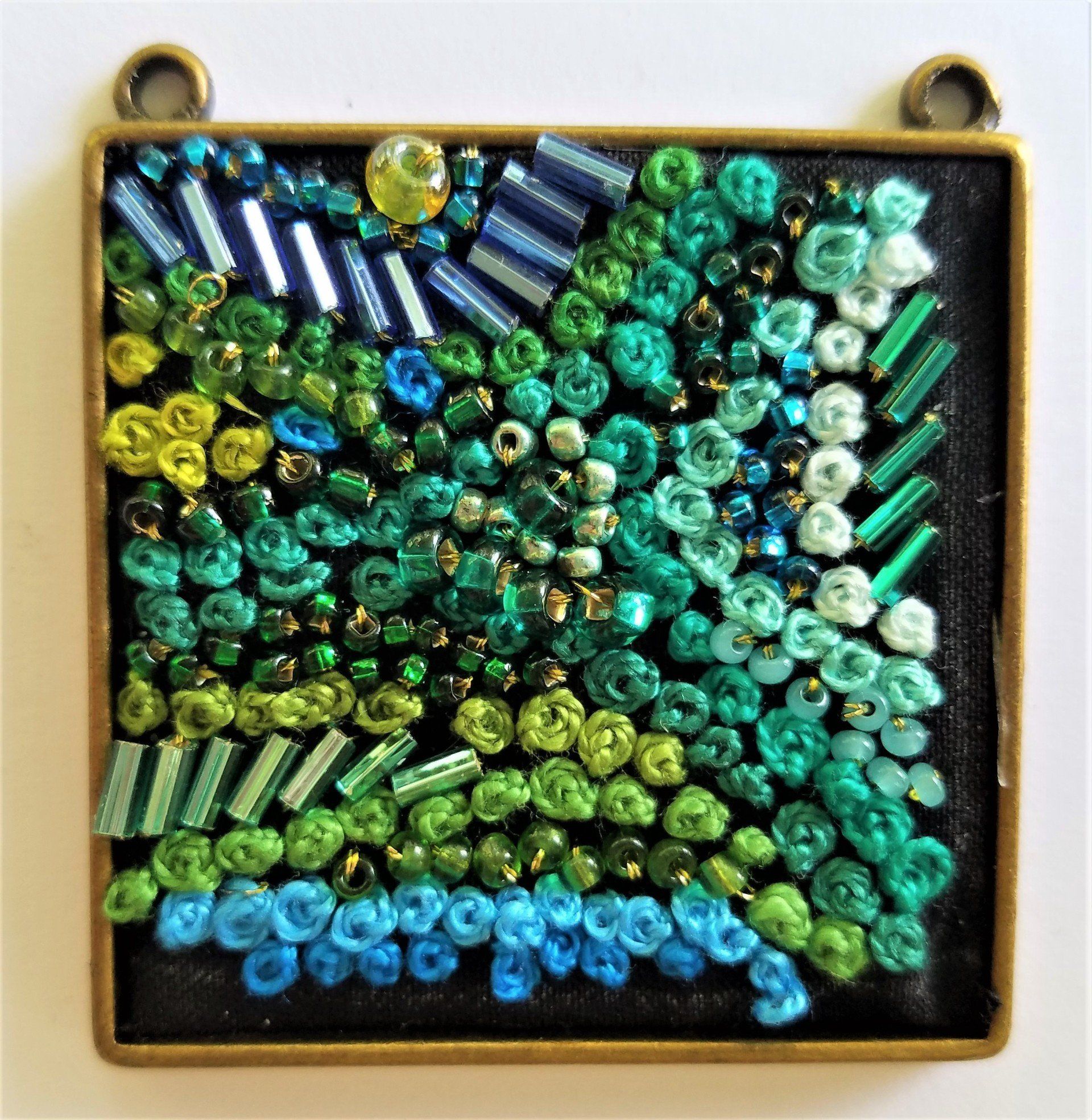 A display of green and blue beads on a black background