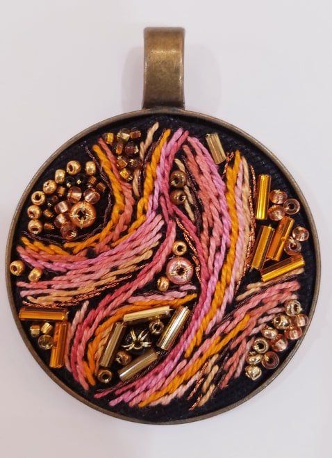 A pendant with embroidery and beads on it