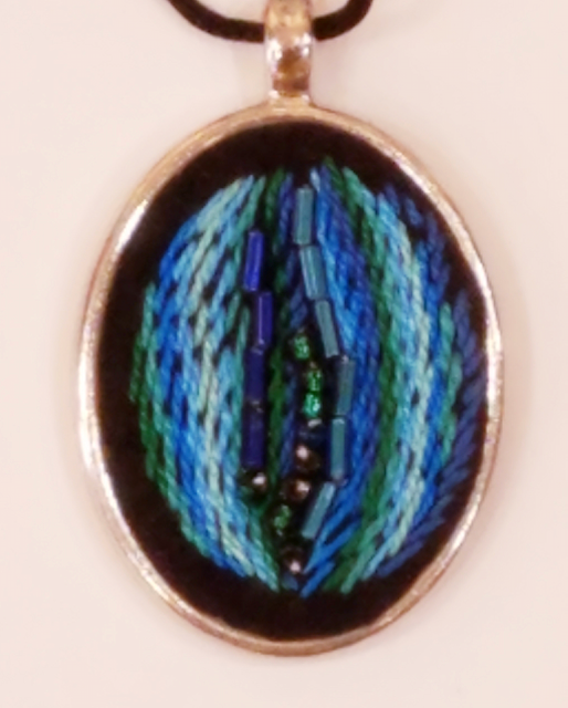 A round pendant with blue and green beads on it