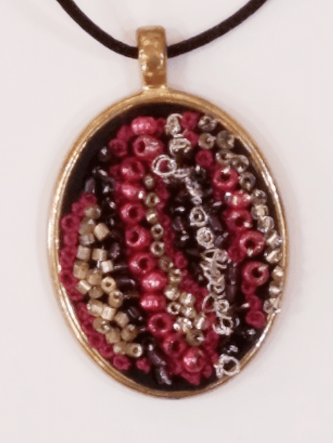 A gold pendant with red and black beads on it