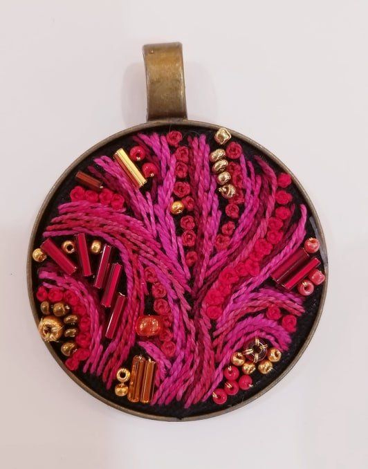 A round pendant with pink and gold beads on it