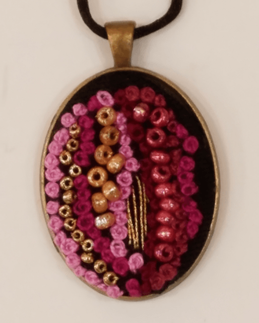 A pendant with pink and gold beads on it