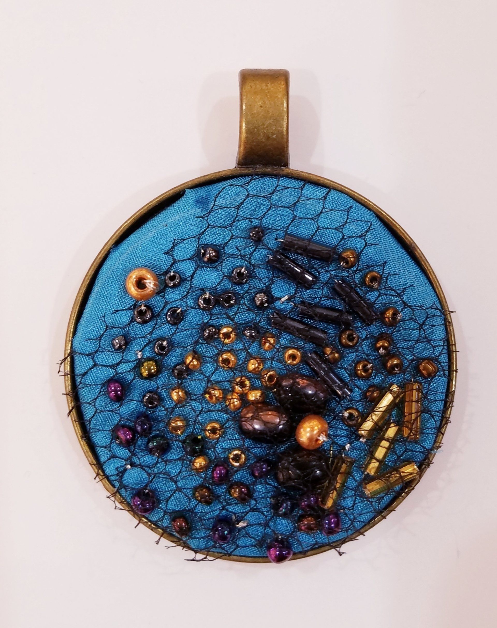 A blue and gold pendant with beads on it