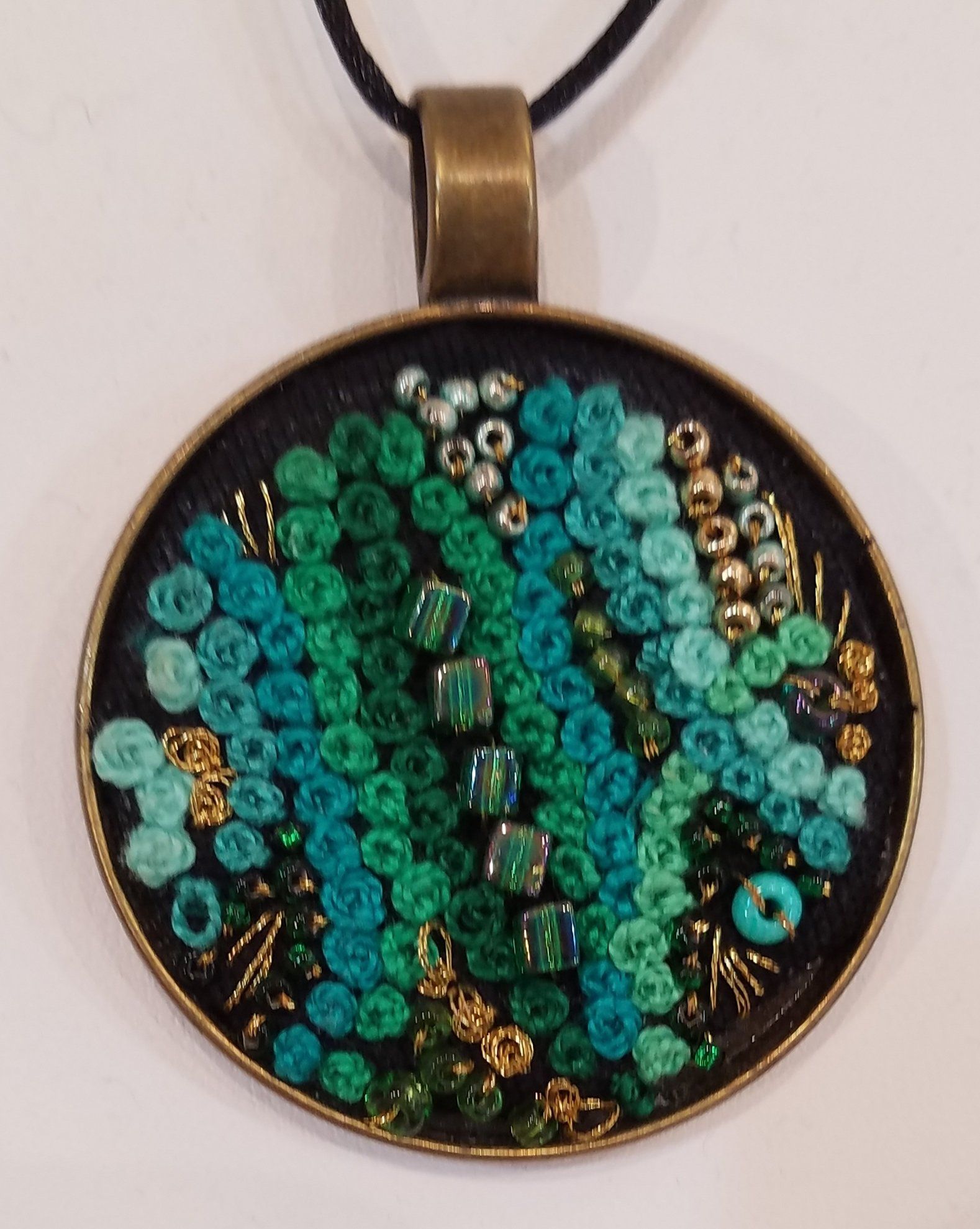 A pendant with green beads on a black background