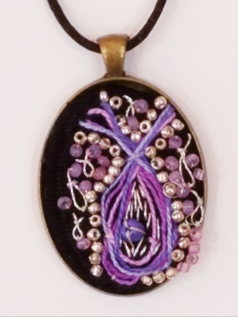 A black pendant with purple beads on it