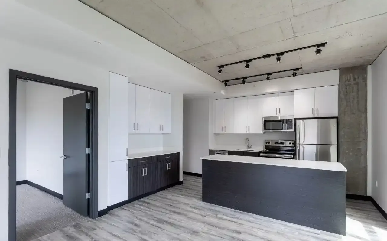 Modern kitchen with an island, white upper cabinets, dark lower cabinets, and stainless steel appliances.