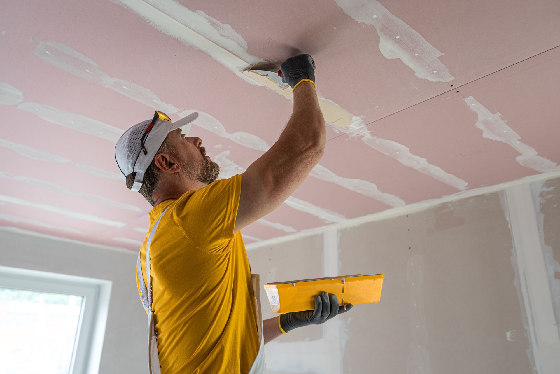 A man is plastering a ceiling with a trowel.