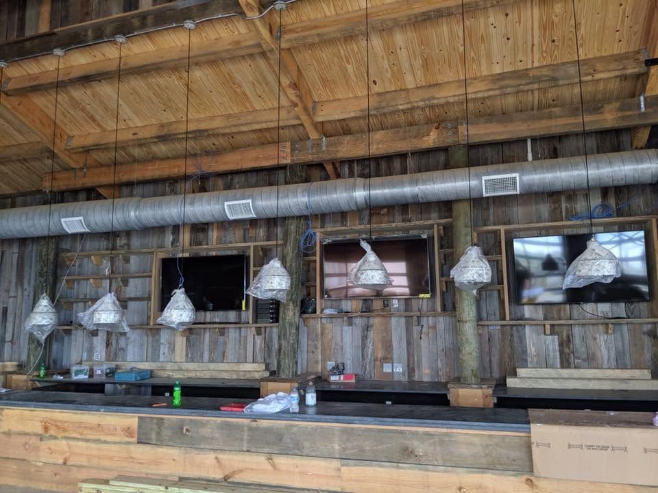 Rustic barn interior with hanging metal lights, wooden stalls, and a long counter.