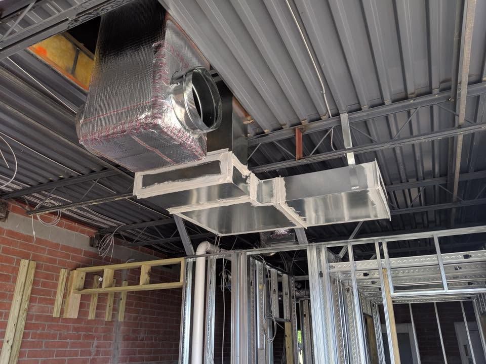 Exposed ceiling ductwork and metal HVAC vents in an unfinished interior construction site