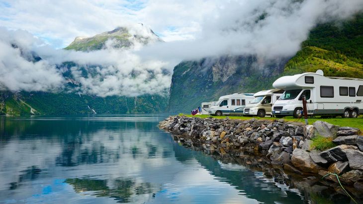 Hands in orange gloves working on electrical wiring in a wall.