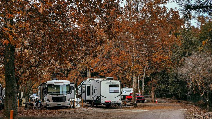 RV kitchen with sink, stove, cabinets, and a window. Wooden cabinets and light interior.