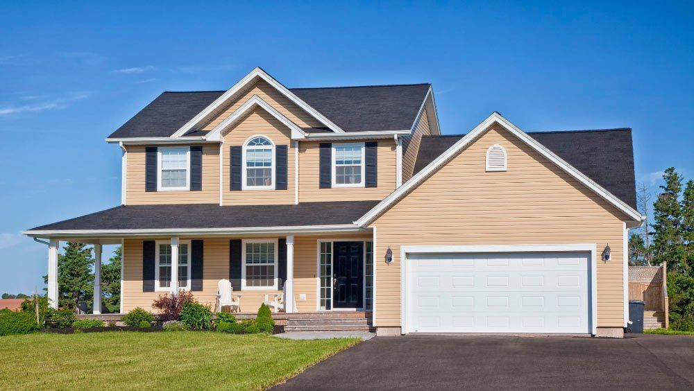 A large house with a white garage door and black shutters.