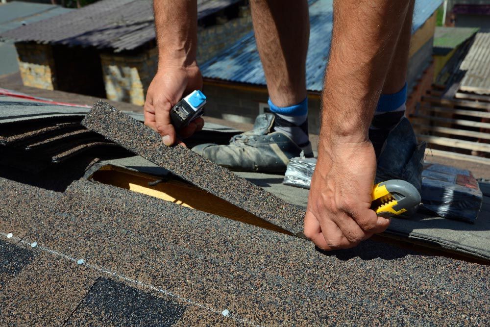 A man is working on a roof with a tape measure.