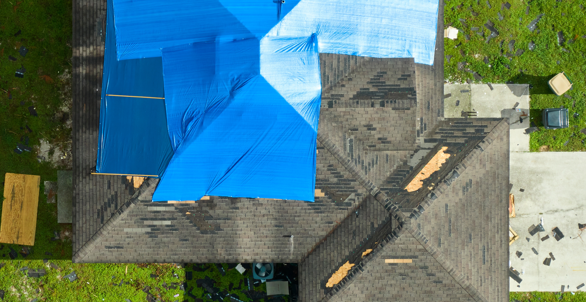 An aerial view of a house with a blue tarp on the roof.