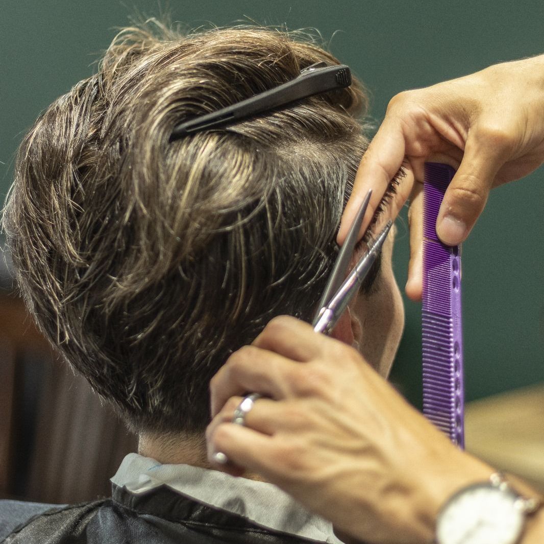 Un barbero le corta el pelo a un hombre con barba.