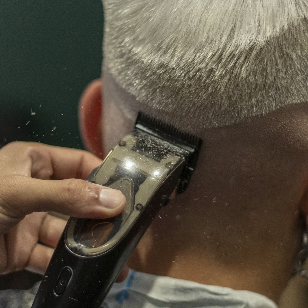 Un barbero le está cortando el pelo a un hombre con una maquinilla.