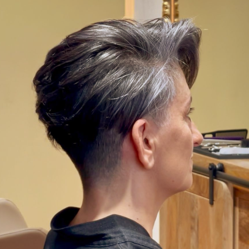 Un barbero le está cortando el pelo a un hombre con una maquinilla.