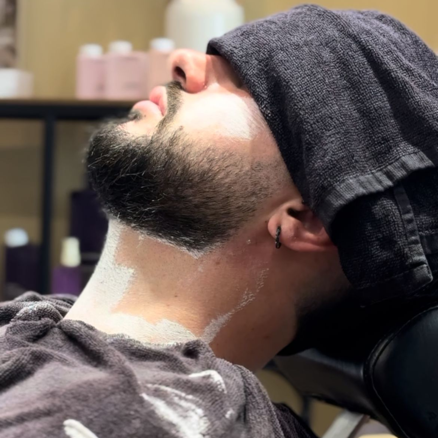Un hombre con un tatuaje en la mano se está afeitando la barba