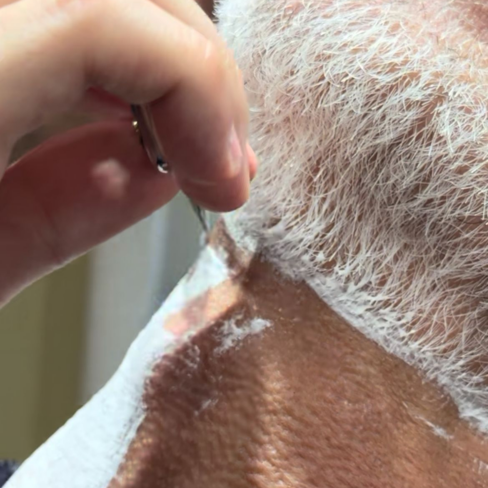 Un barbero le está cortando la barba a un hombre