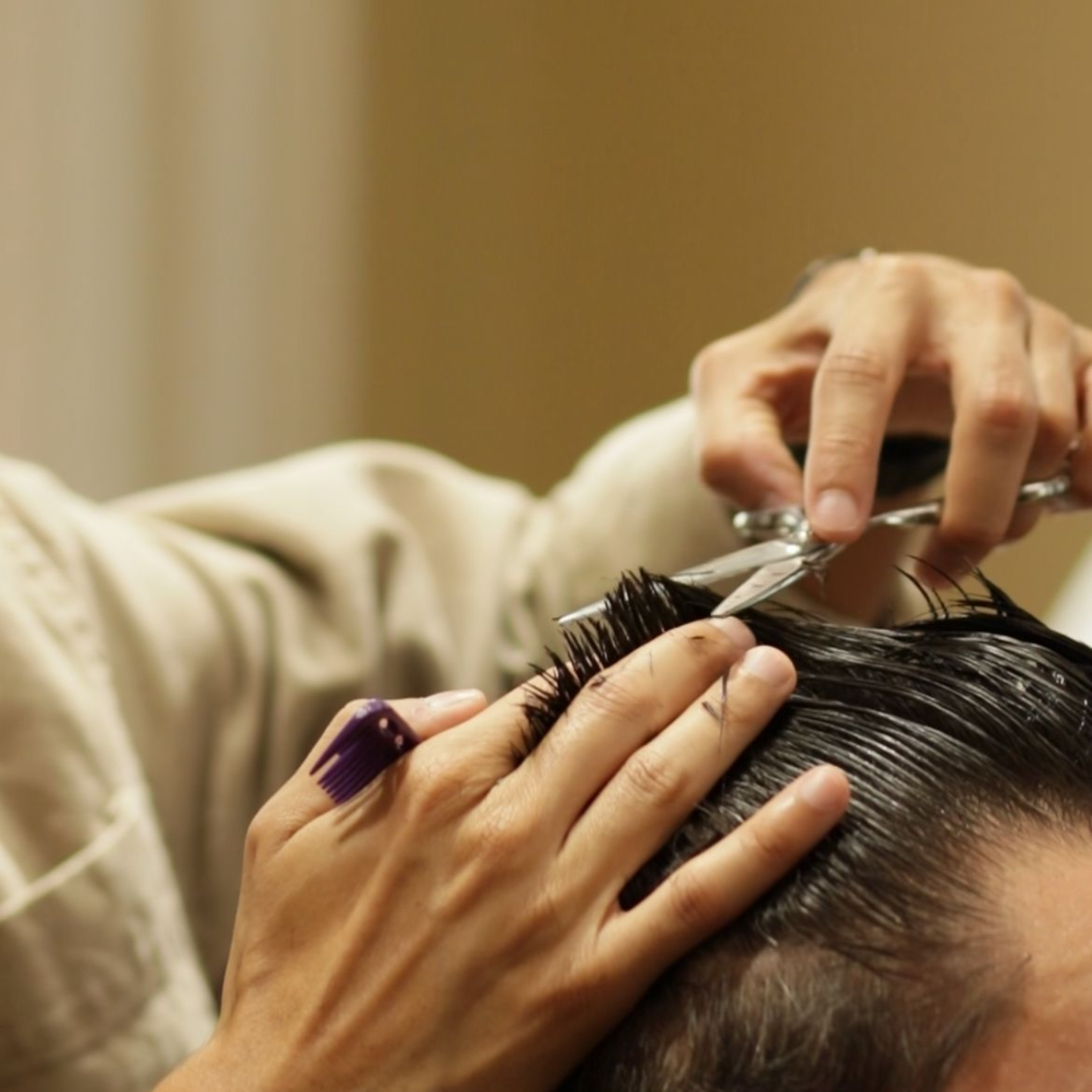 Un barbero le corta el pelo a un hombre con barba.