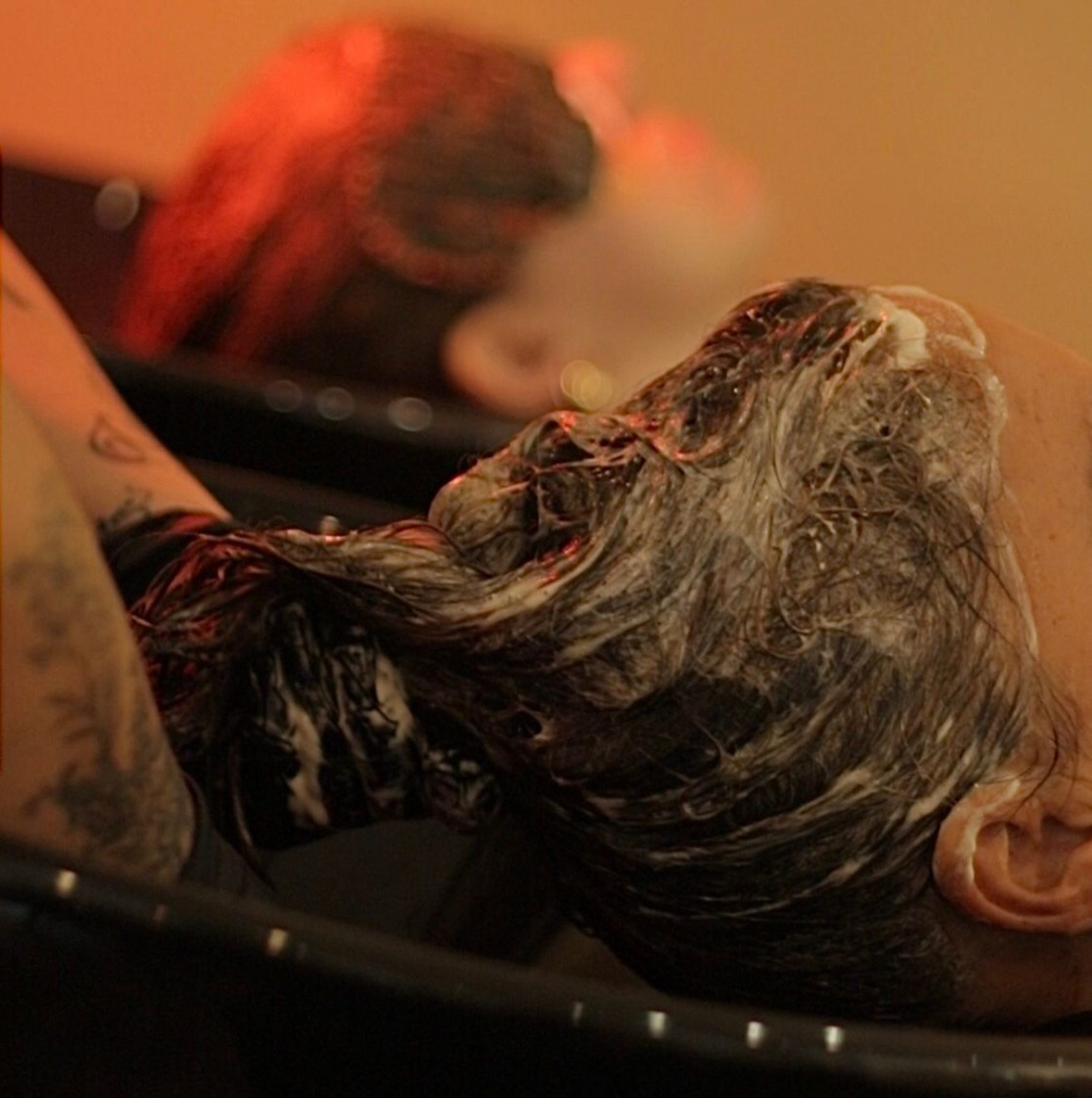 Una mujer se lava el pelo en un lavabo.