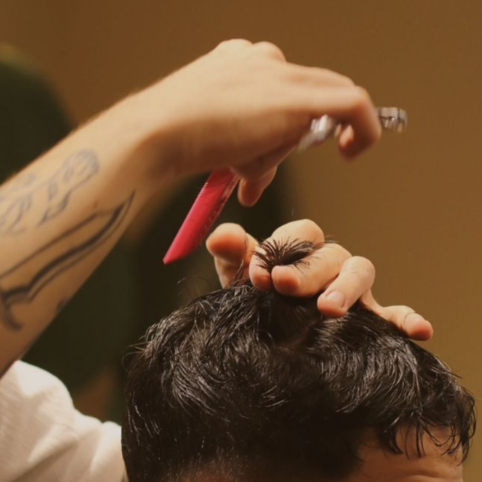 Un barbero le está cortando el pelo a un hombre.