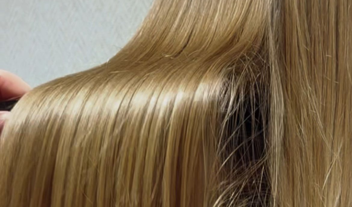 Una mujer está siendo peinada por un peluquero en un salón.