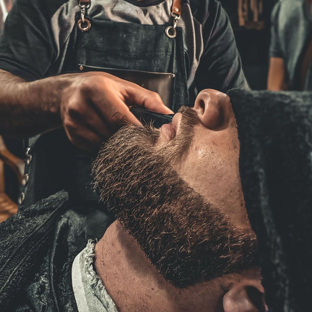 Un barbero le afeita la barba a un hombre.