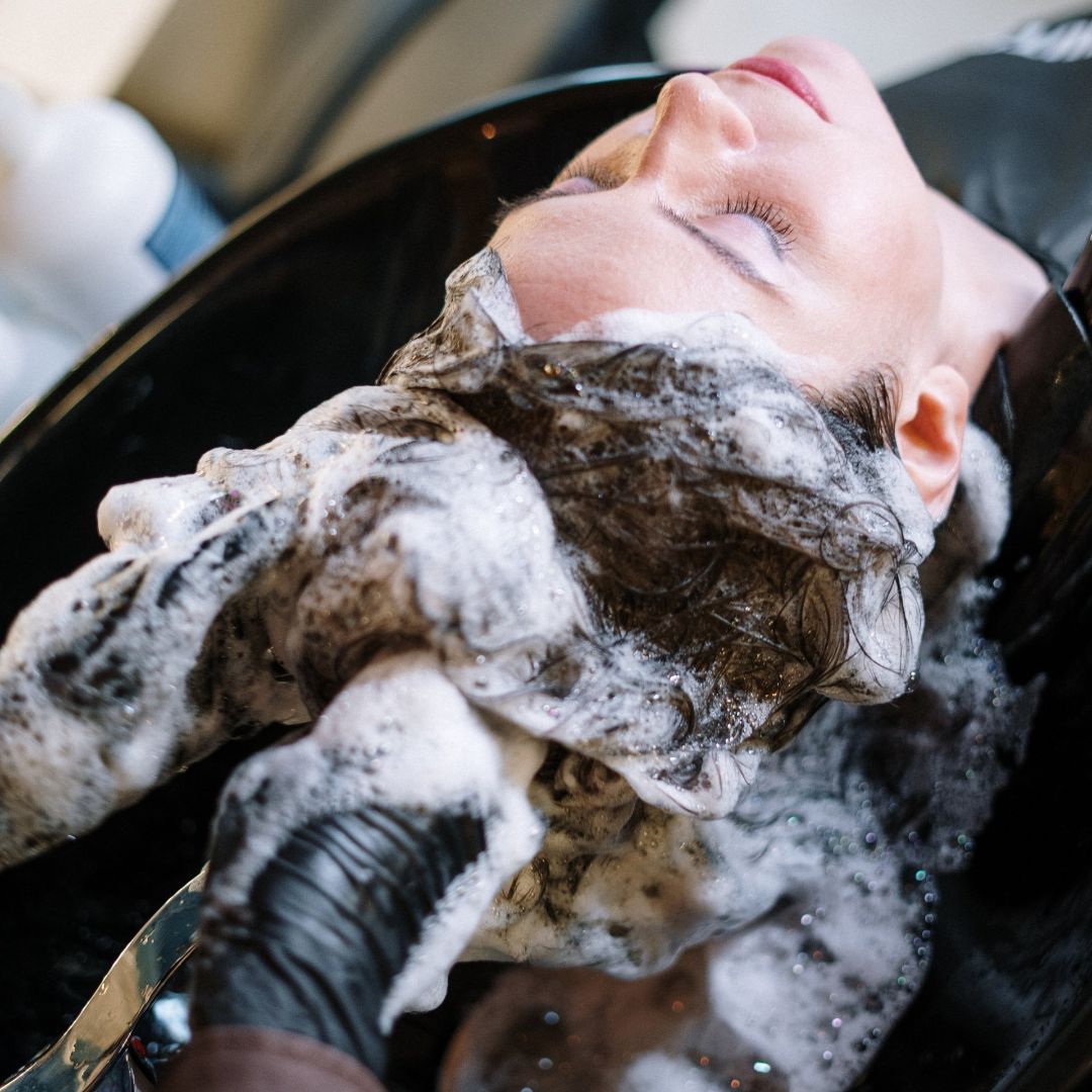 Una mujer se lava el pelo en un lavabo.