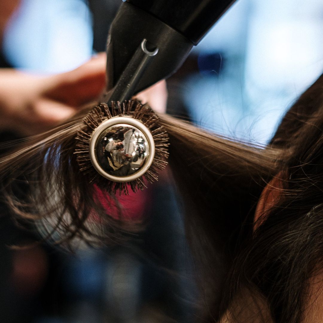 Una mujer secándose el cabello con un cepillo redondo