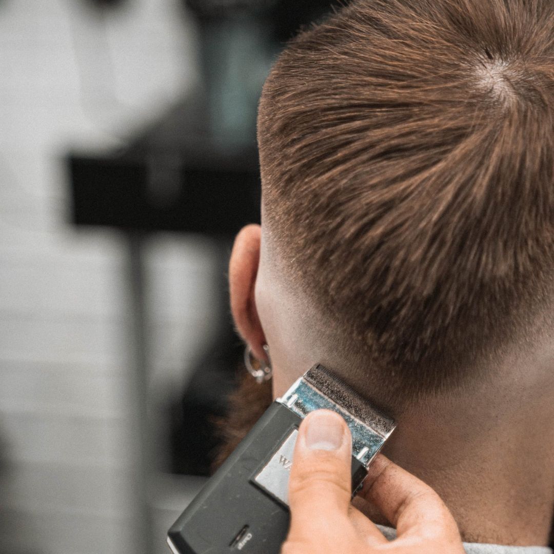 Un barbero le está cortando el pelo a un hombre con una maquinilla.