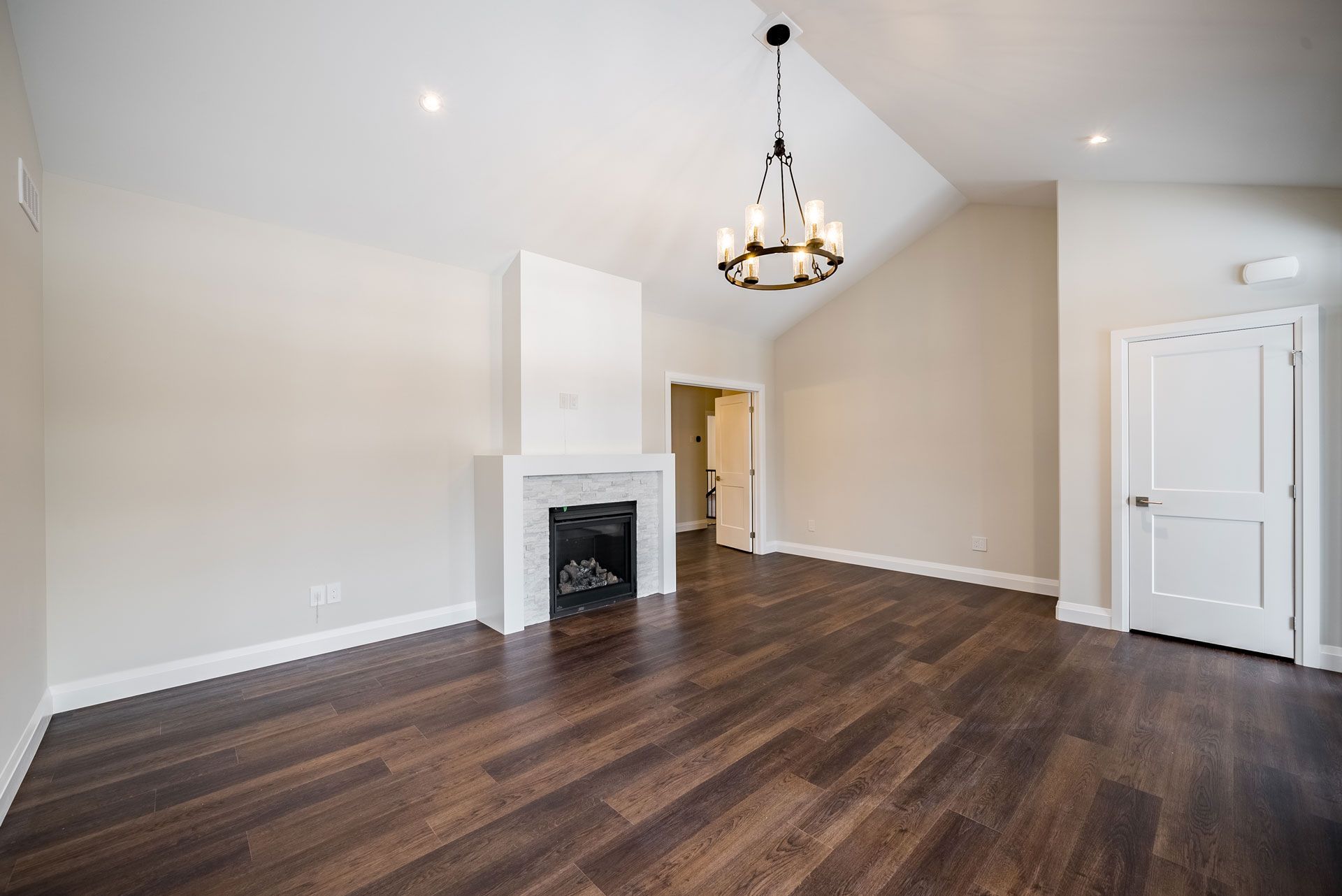An empty living room with a fireplace and a chandelier in a Fidelity Homes Signature Build in Warkworth Ontario