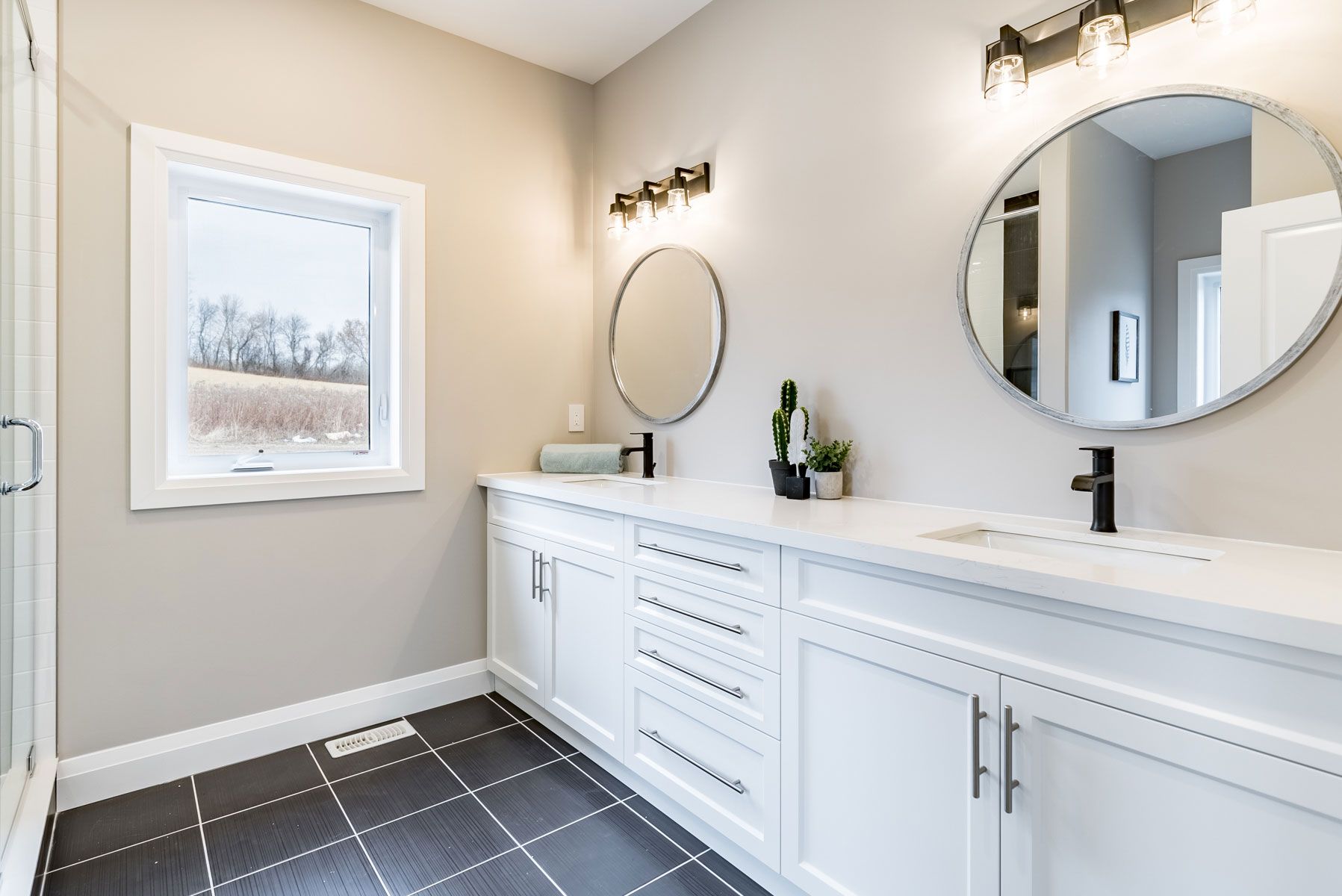 A bathroom with two sinks and two mirrors at a Fidelity Homes Signature build in Cramahe Township