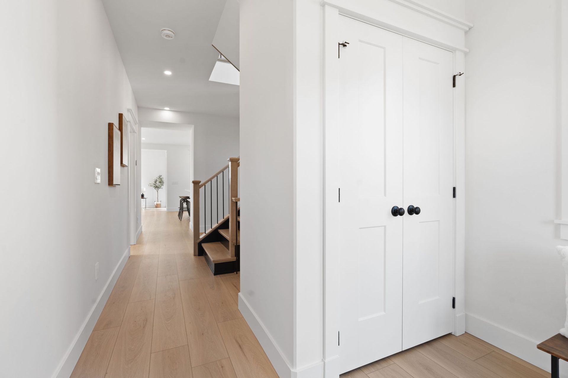 A hallway in a house with white walls and wooden floors leading to a staircase in Colborne Ontario