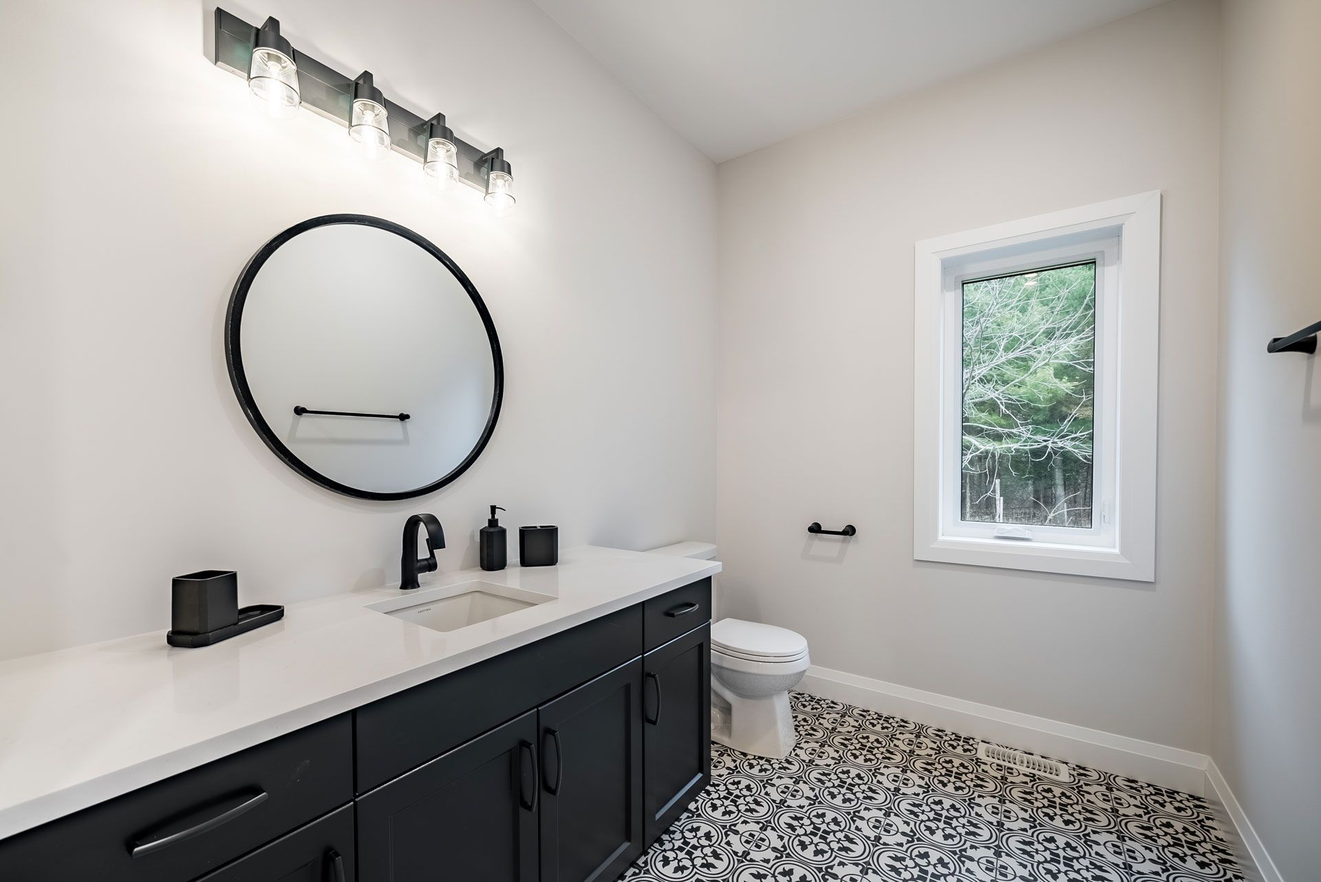 A bathroom with a sink , toilet , mirror and window Fidelity Homes Signature build in Cramahe Township