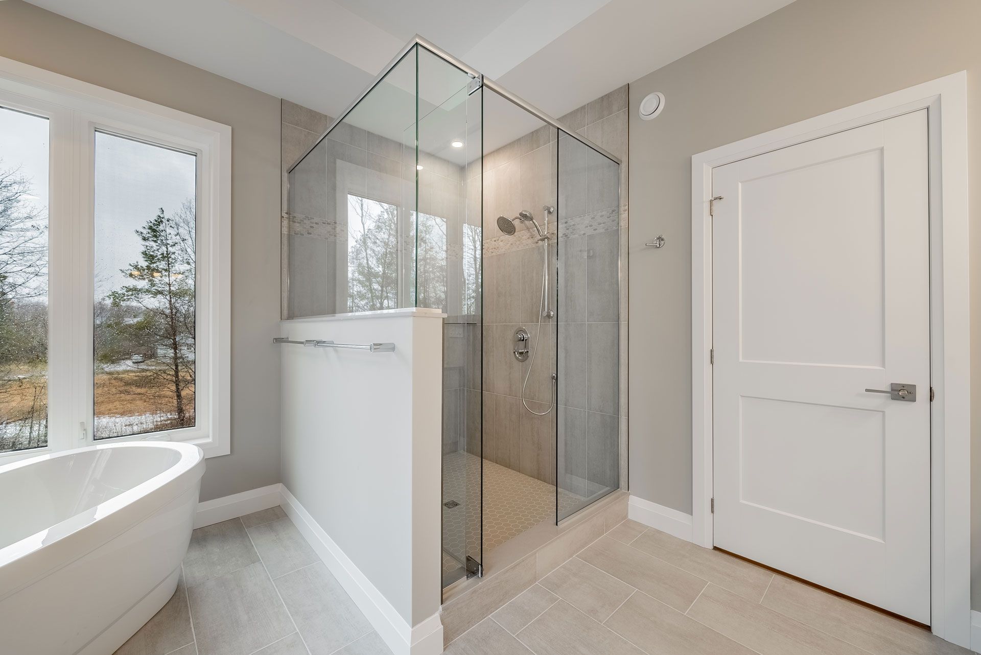 A bathroom with a walk in shower and a bathtub in Fidelity Homes Signature build in Cramahe Township