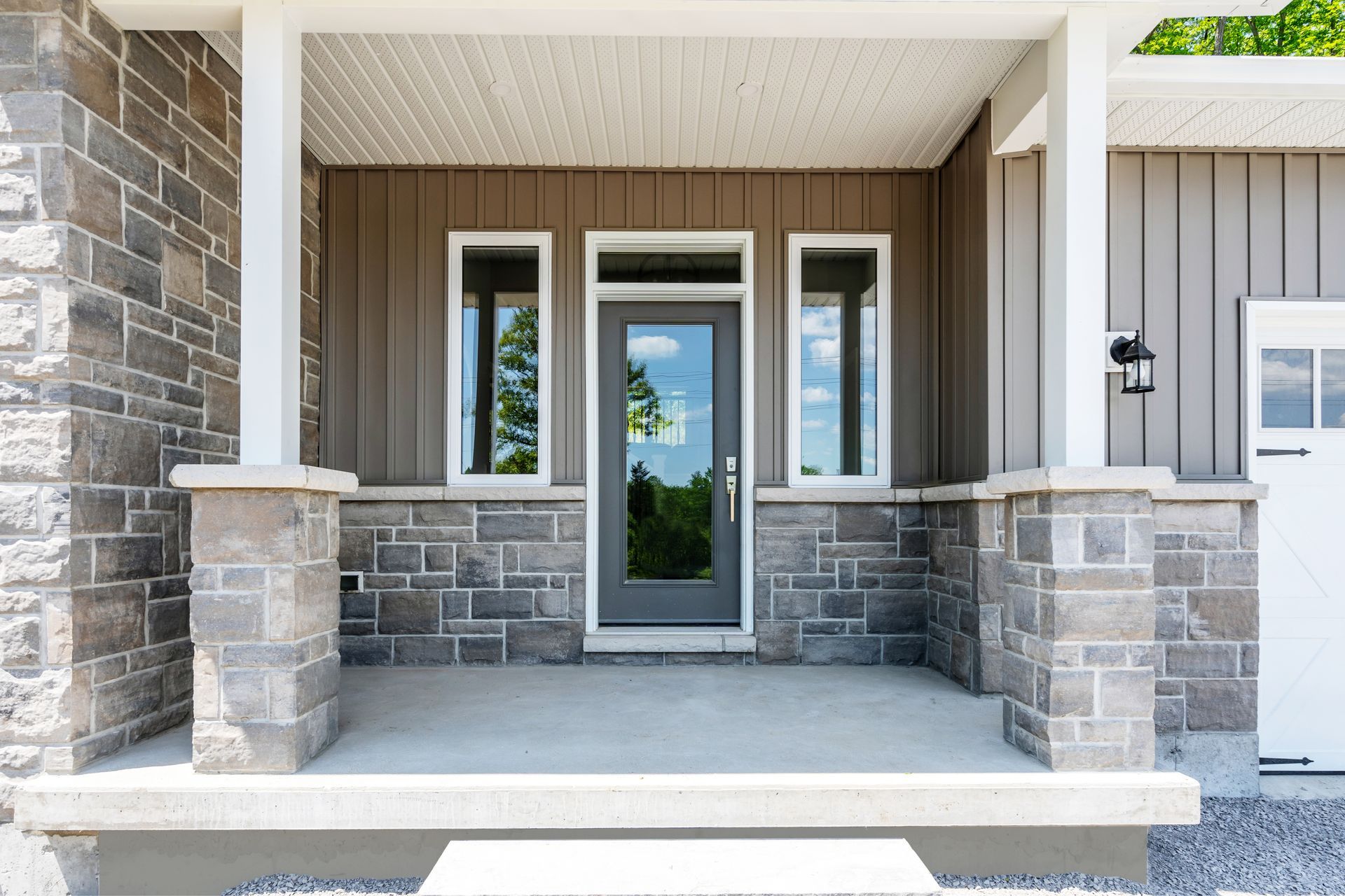 A Fidelity Homes custom build with a porch and a gray door in Castleton