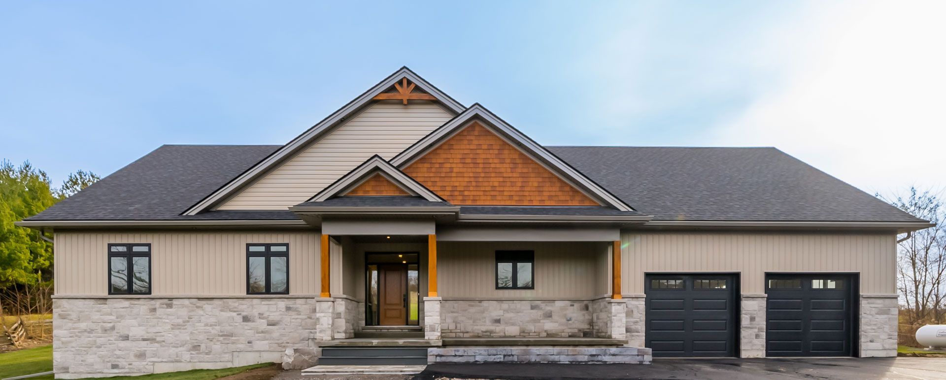 A large Fidelity Homes signature build with a grey roof and black garage doors