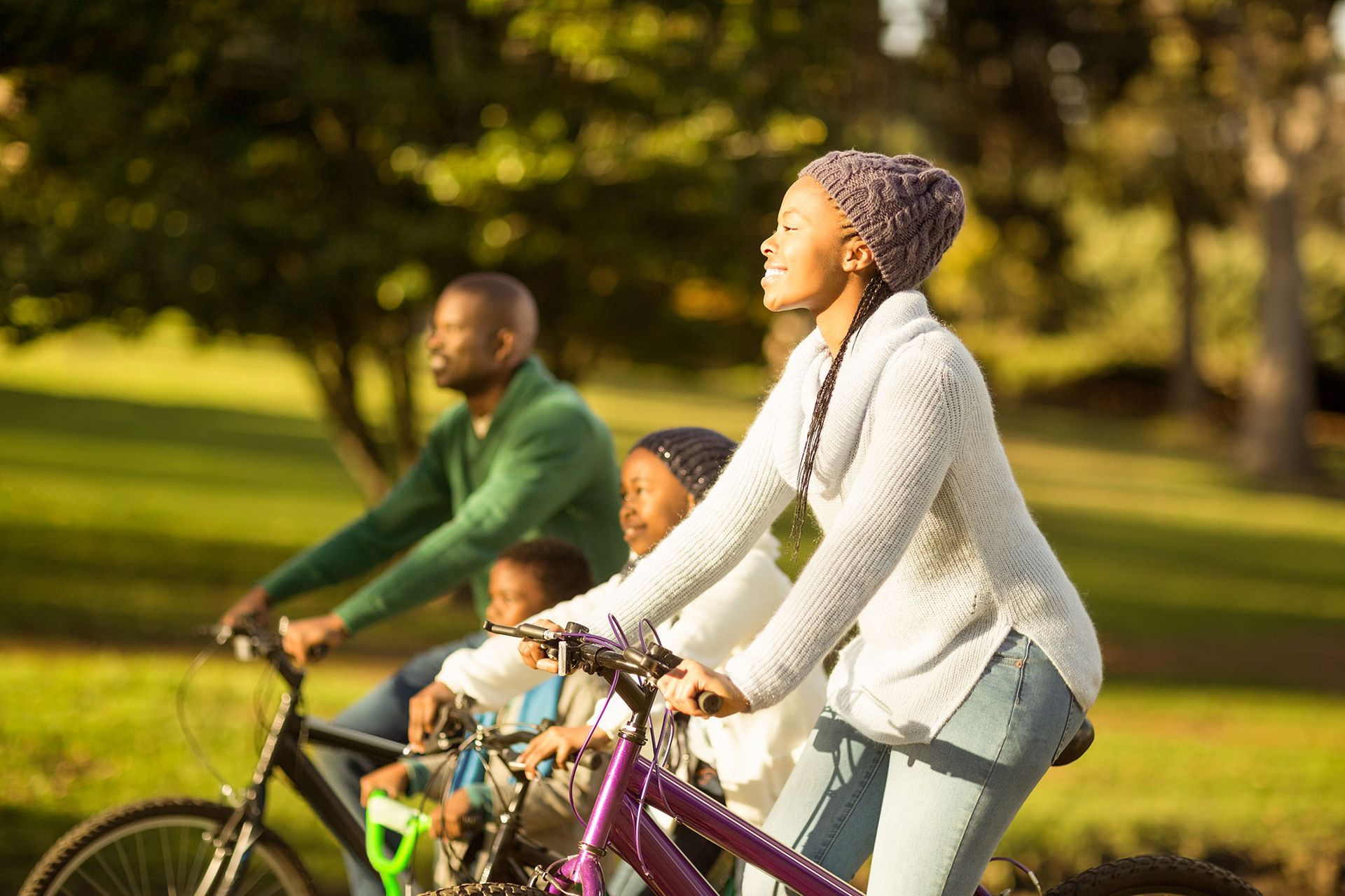 A family is riding bikes in a park on a sunny day