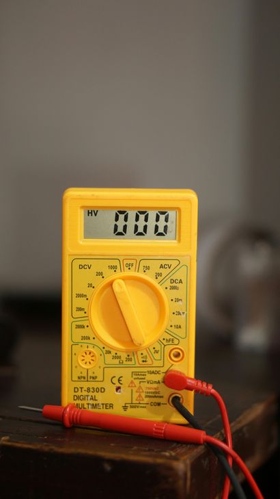 Yellow digital multimeter showing 0.00 with red probes attached