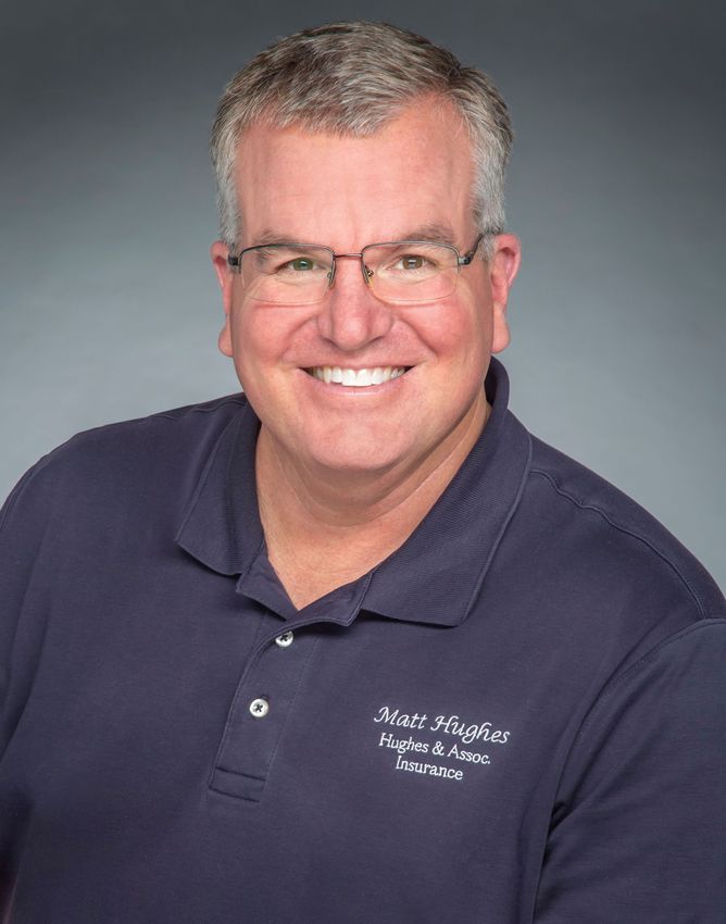 A man in a suit and white shirt is smiling for the camera.