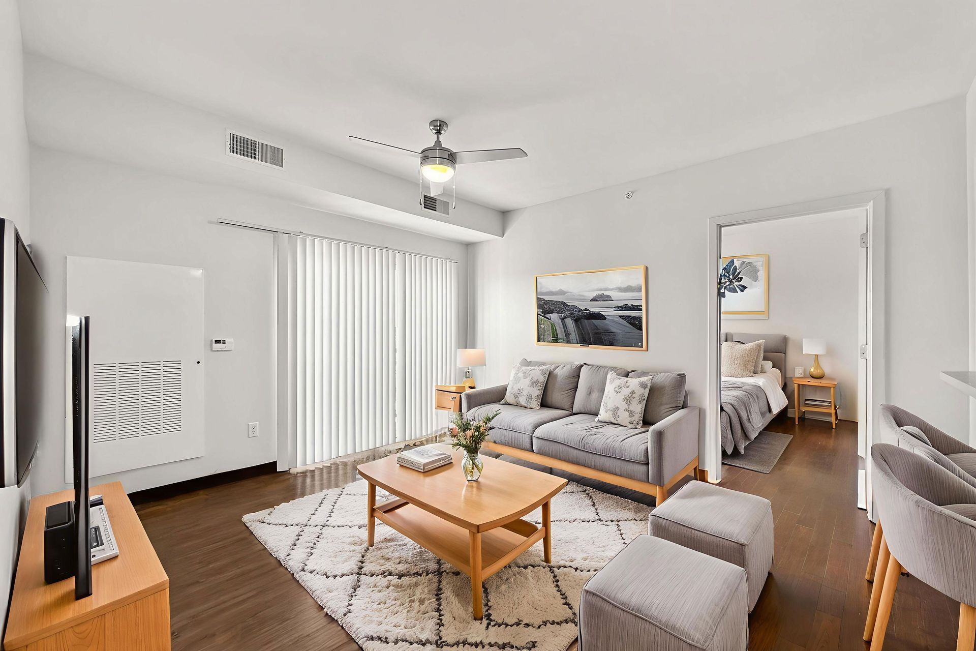Apartment building with stone accents, balconies, and parked cars on a grassy lawn under a blue sky.