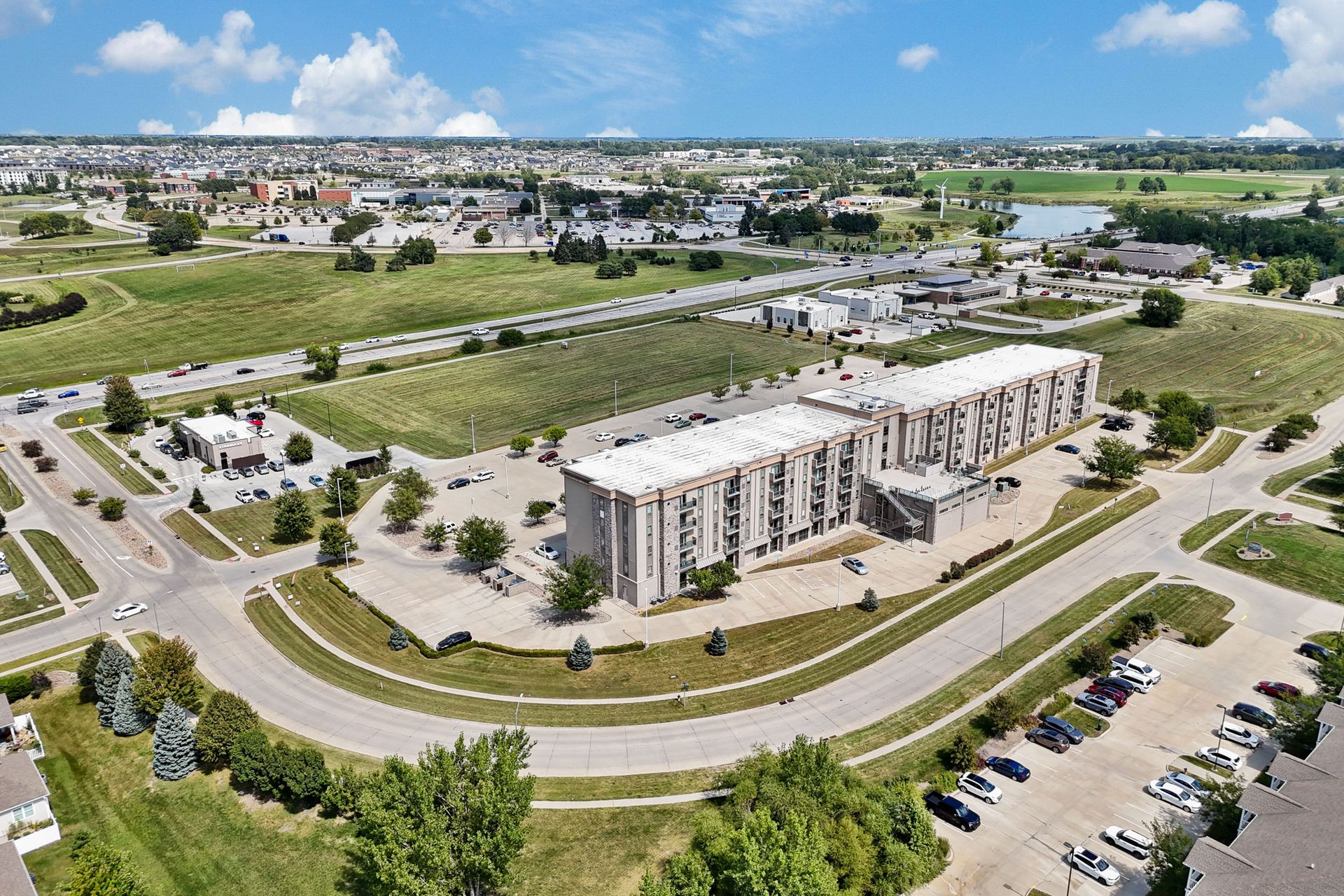 Kitchen with dark brown cabinets, stainless steel appliances, and white countertops; opens to a living area with green armchair.