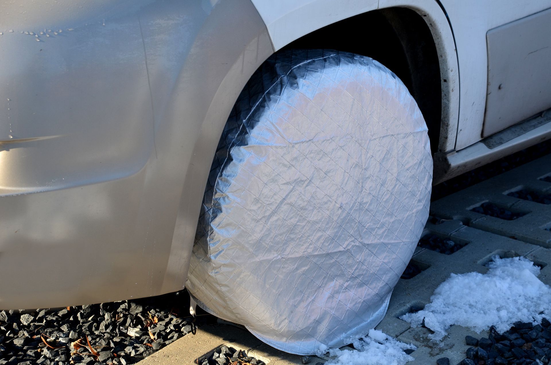 A car with a tire cover on it is covered in snow.